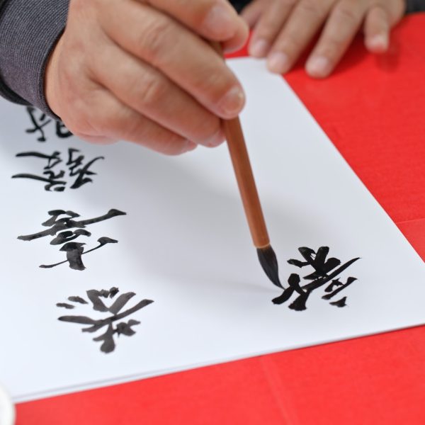 Old man writing Chinese calligraphy for lunar new year words means happy new year